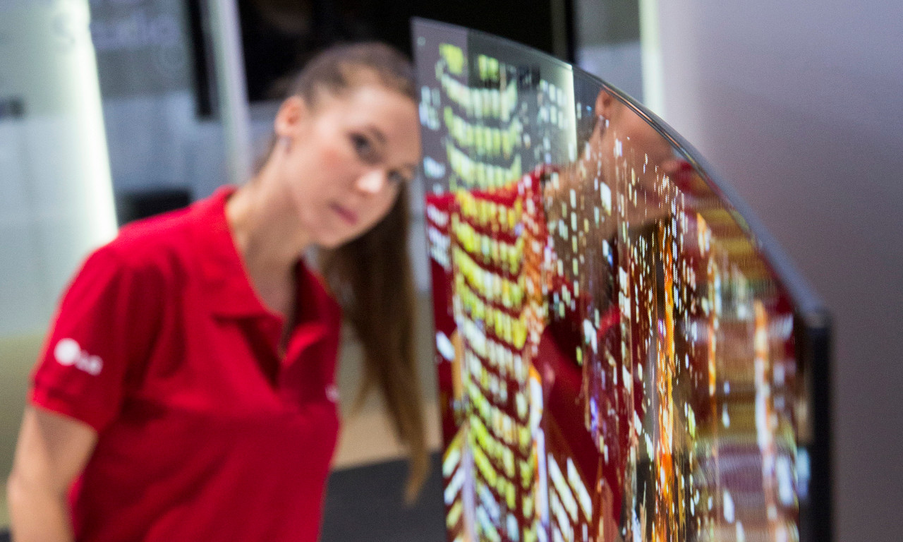 An employee of LG Electronics looks behind a curved organic light-emitting diode, oled, television screen at IFA, one of the world's largest trade fairs for consumer electronics and electrical home appliances, in Berlin, Germany, Thursday, Sept. 5, 2013. The screen is just 4.3mm, 0.17 inches, thin and weighs just 17 kilograms, 37.48 pounds, IFA will take place on the Berlin Exhibition Grounds from Sept 6 to 11, 2013. (AP Photo/Gero Breloer)