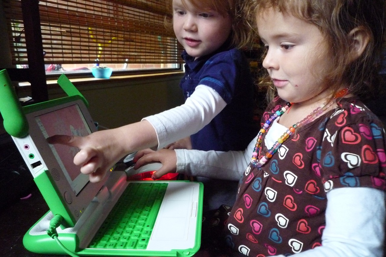Презентабельных фотографий своего ноутбука у меня пока не получилось, а в Сети его снимков давно нет. Поэтому иллюстрируют сегодняшнюю колонку просто случайные кадры так или иначе связанные со старой цифровой техникой. Здесь, к примеру, дети играют с нашумевшей в своё время портативной персоналкой OLPC образца середины нулевых. Она старая и медленная, но для ребёнка она интересней «настоящих компьютеров», потому что может ему принадлежать.