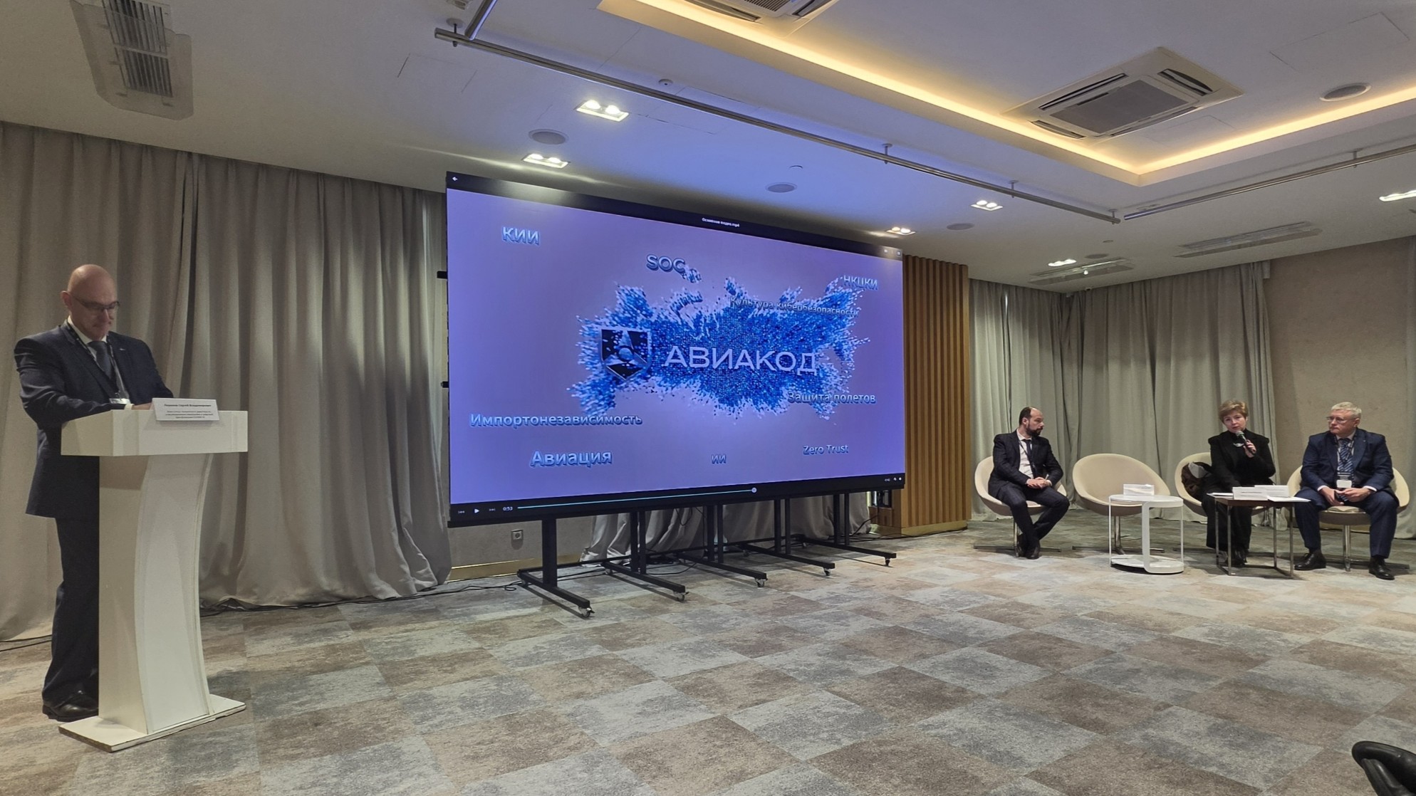 Пленарная сессия «Авиакод-2026»: выступающий у трибуны и экран с логотипом конференции