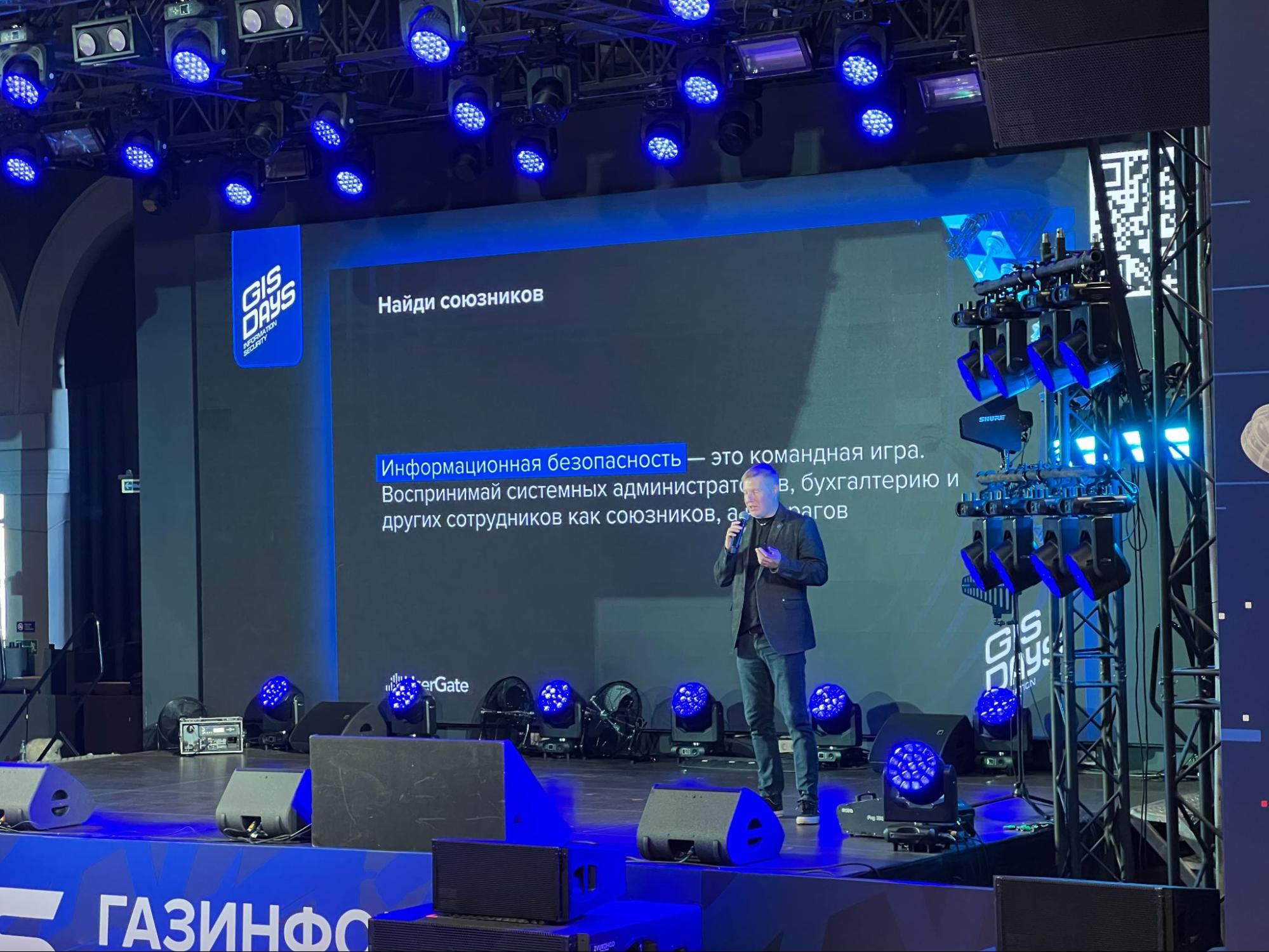 Спикер на сцене GIS STUDENT DAY 2026 со слайдом «Найди союзников» о командной игре в информационной безопасности