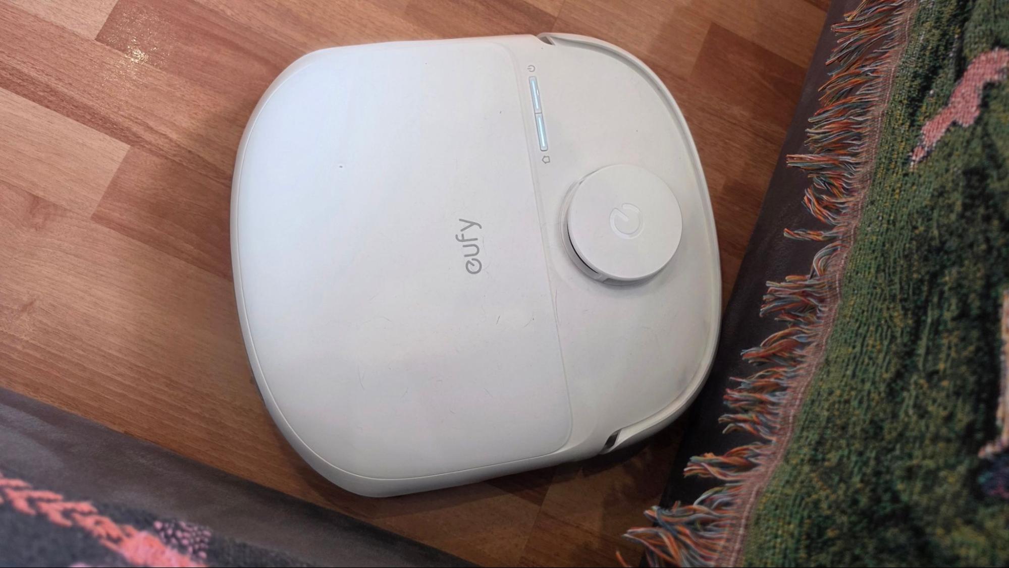 Робот-пылесос Eufy Omni C28 у ковра с бахромой на деревянном полу