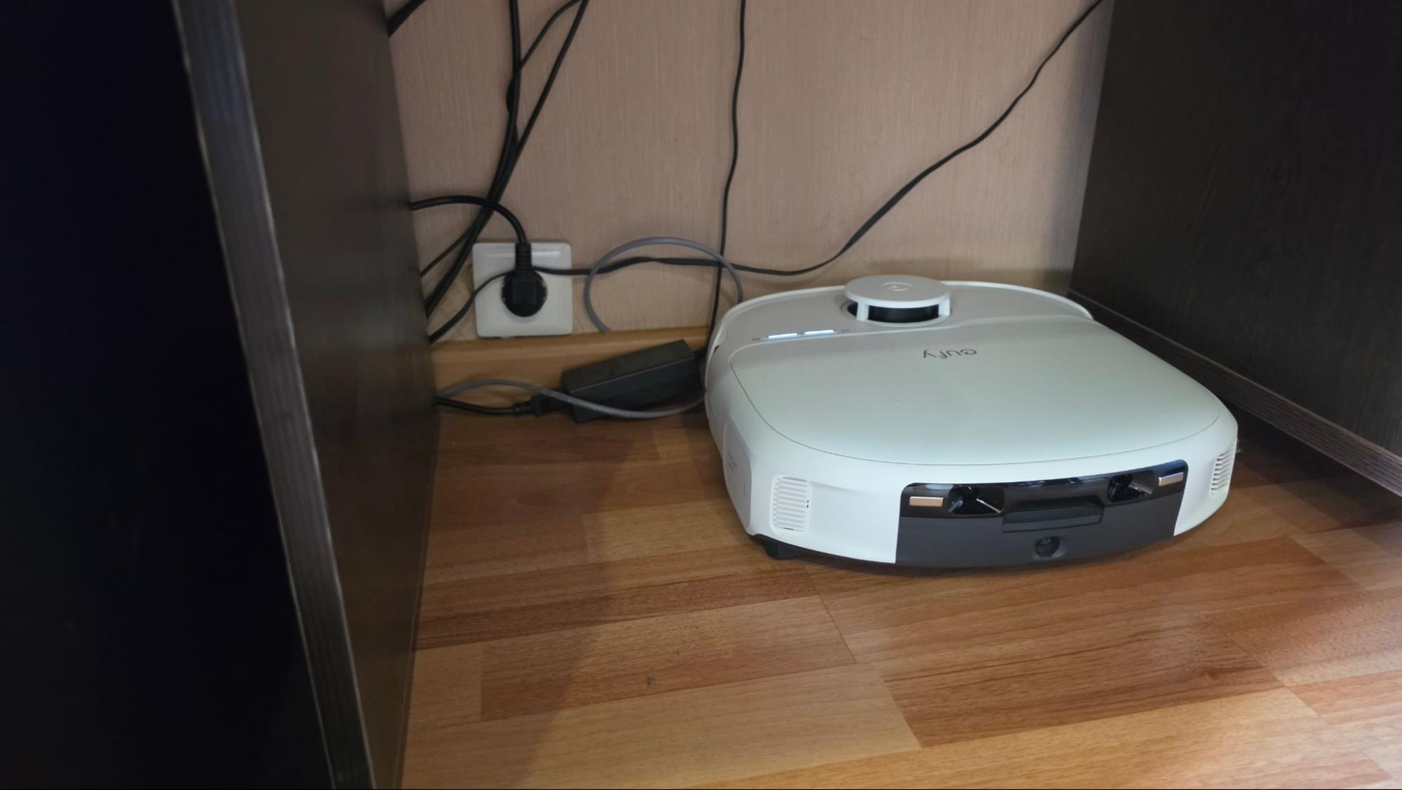 Робот-пылесос Eufy Omni C28 у стены с розеткой и проводами