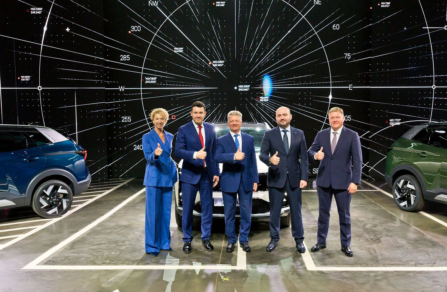 Пять человек в деловых костюмах позируют между синим и зеленым автомобилями LADA
