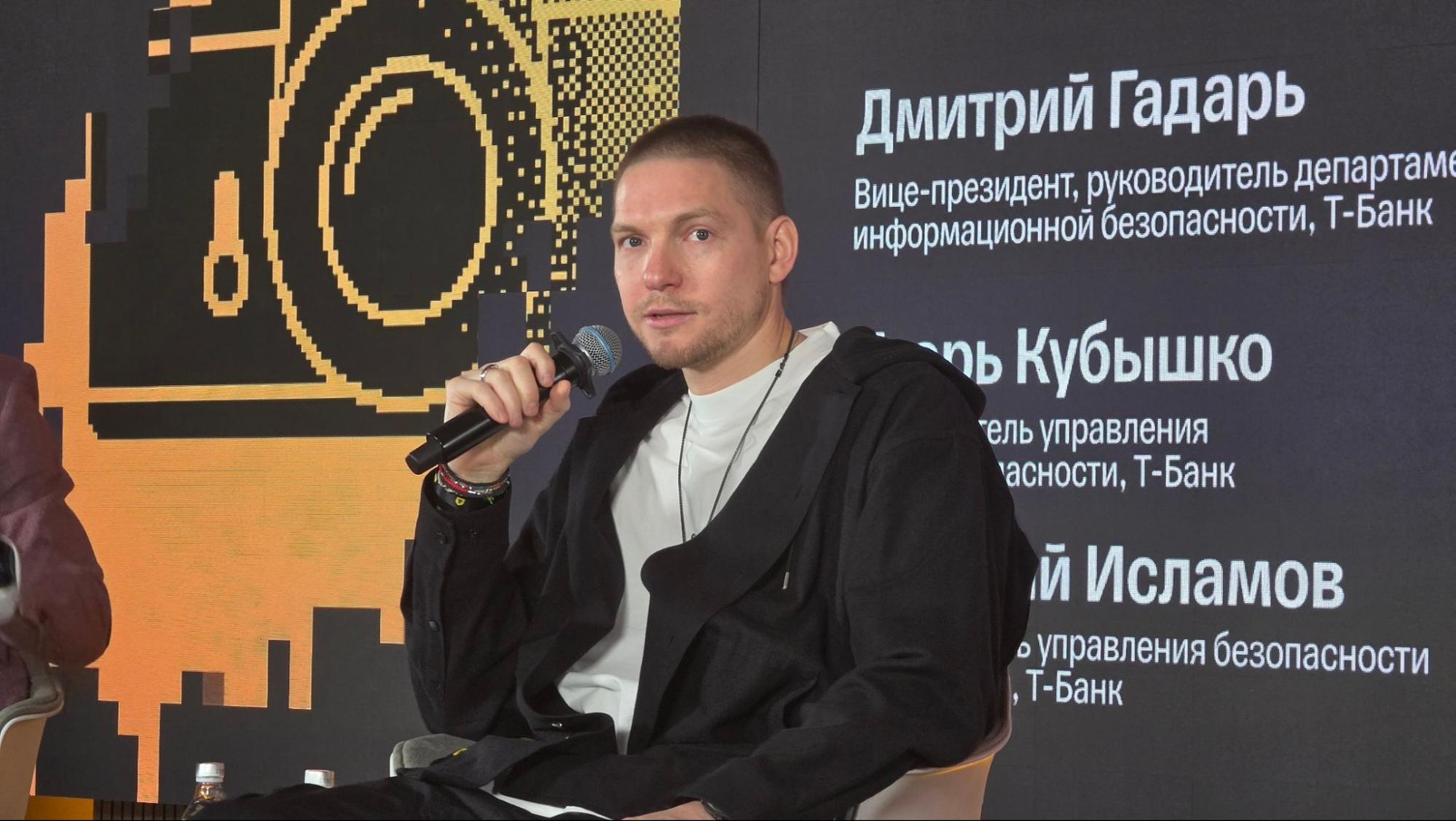 Спикер с микрофоном на фоне экрана с именами руководителей ИБ Т-Банка