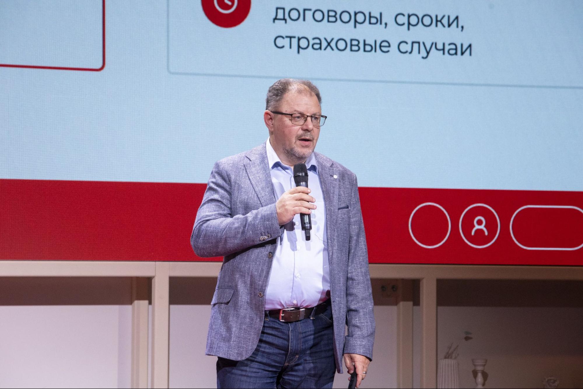 Выступающий на сцене на фоне слайда про договоры, сроки и страховые случаи